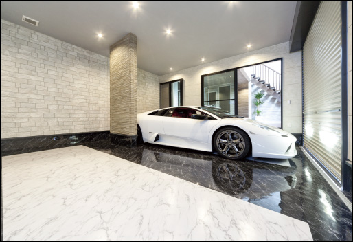 美しいガレージには美しい車が佇んでいる。中庭や外庭など使われる大理石調のフロアタイルを床に使用。当初は黒一色の予定だったが、空間が重くなり過ぎないよう白を組み合わせる提案が映えている